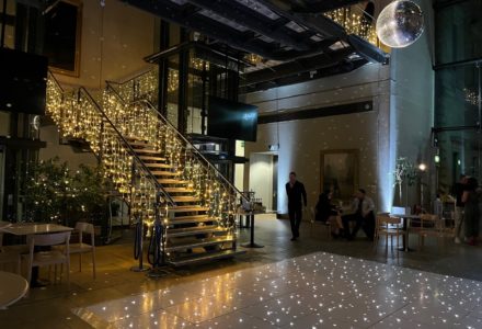 Atrium - fairy lights on glass stairs and mirror ball and dance floor set up for a party