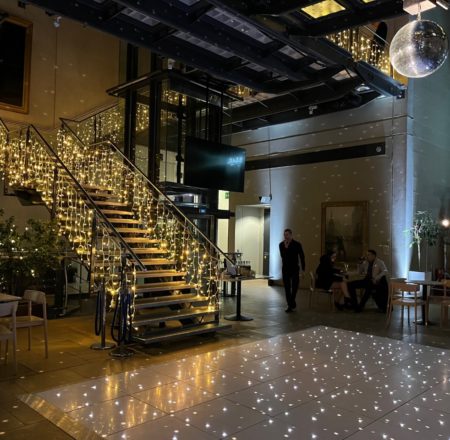 Atrium - fairy lights on glass stairs and mirror ball and dance floor set up for a party