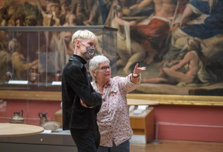 Making Conversation workshop - two people leaning in to talk in front of a painting. The woman has noticed something in the painting and is pointing towards it
