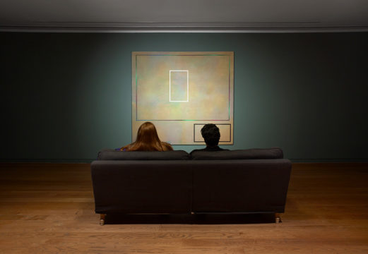 Room to Breathe installation shot- two people sat on a sofa from behind looking at an abstract painting