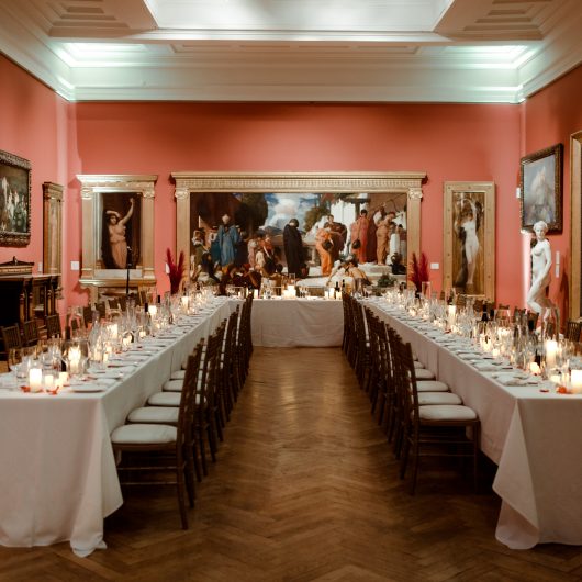 Long tables with table cloths set up in the Victorian Galleries