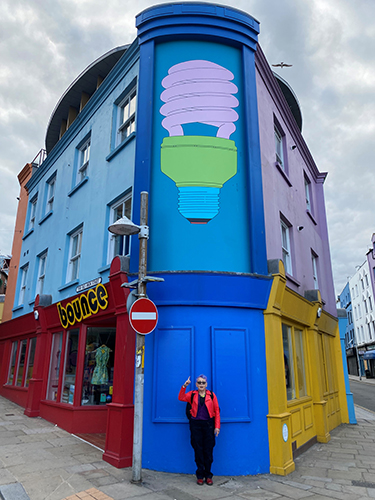 Mindy infront of Michael Craig Martin artwork on the corner of a colourful building
