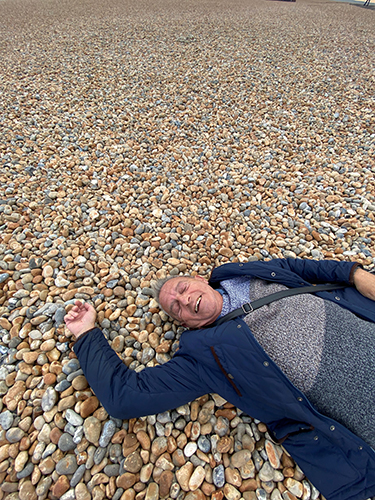 Philip lying on a pebbled Folkestone Beach