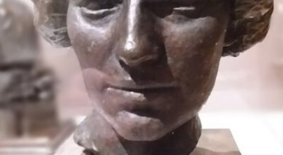 Bronze Head of a woman with short waive hair, open eyes and close lips.